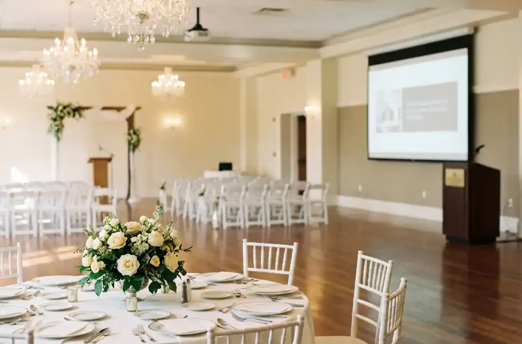 Elegante evenementenhal met ronde tafels, trouwceremonie opstelling en presentatieruimte onder kristallen kroonluchters