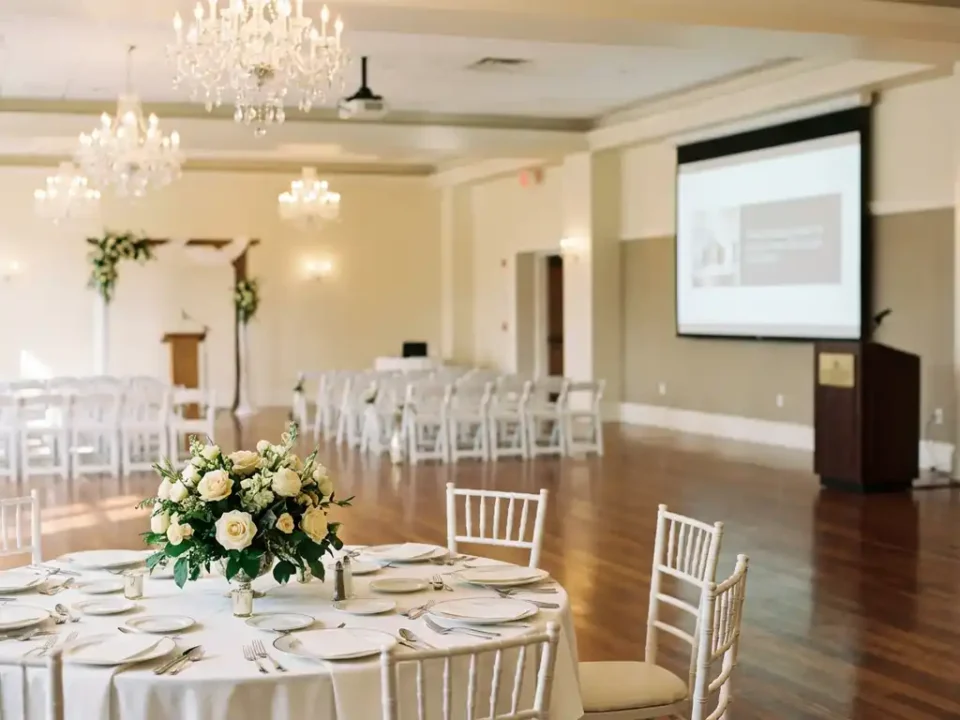 Elegante evenementenhal met ronde tafels, trouwceremonie opstelling en presentatieruimte onder kristallen kroonluchters